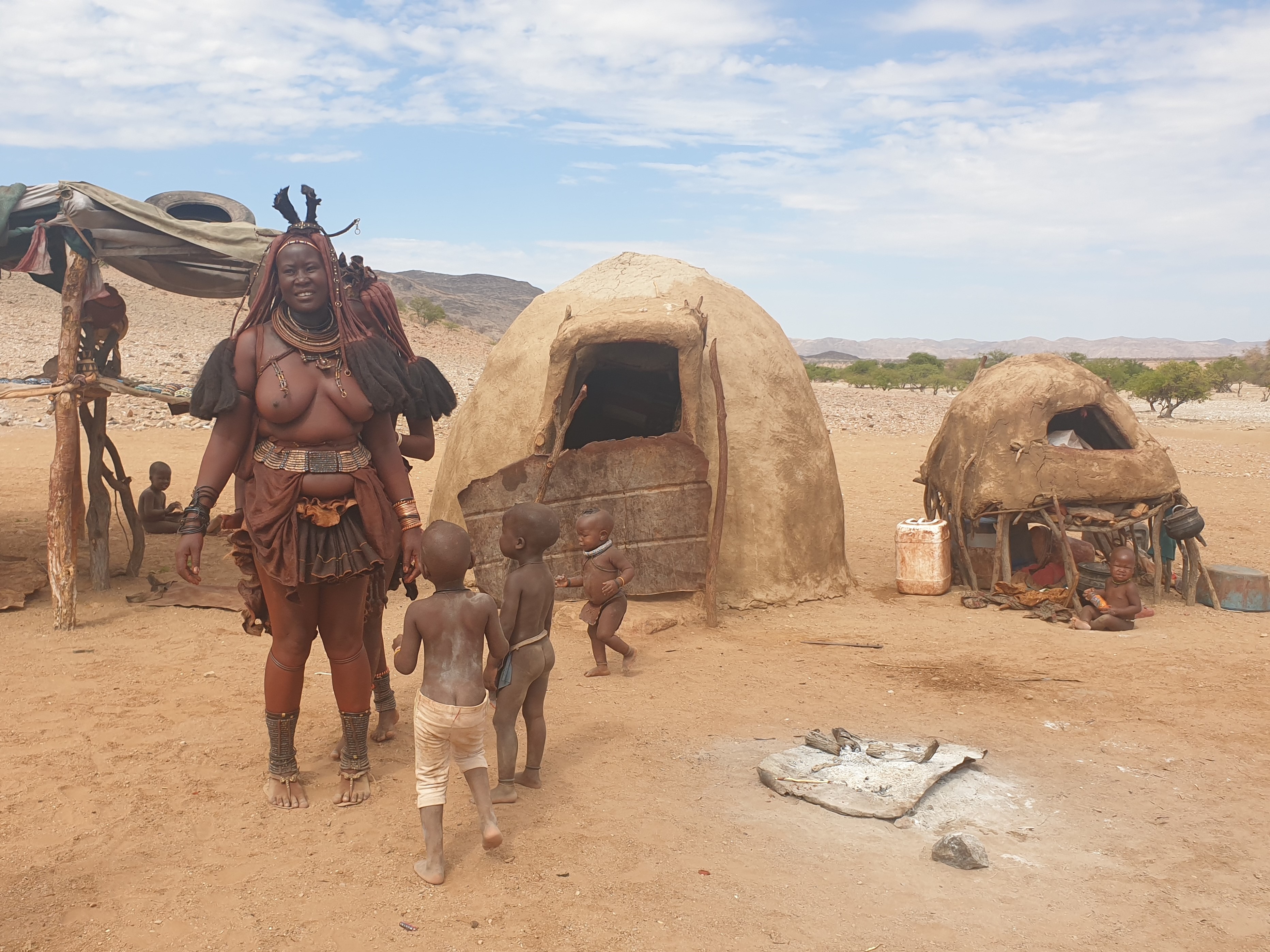 Famille Himba devant d'autres constructions traditionnelles, Désert du Namib, Kaokoland, région de Kunene,Namibie.